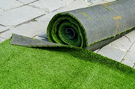 A roll of artificial turf on the ground.