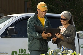 The Grounds Guys service professional showing a customer a tablet.