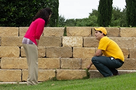 The Grounds Guys service professional talking to a customer next to stone steps.