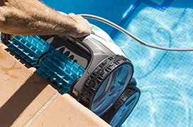 An automated pool cleaner being put into a pool.