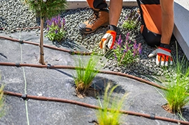 The Grounds Guys service professional installing irrigation piping around arid plants.