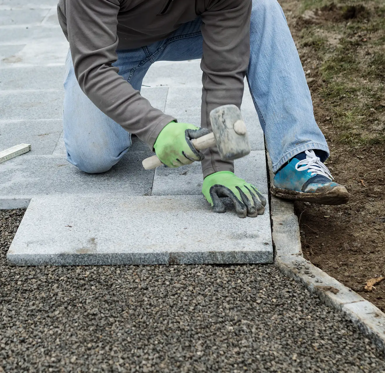 Workers hammering stone plates to install footpath.