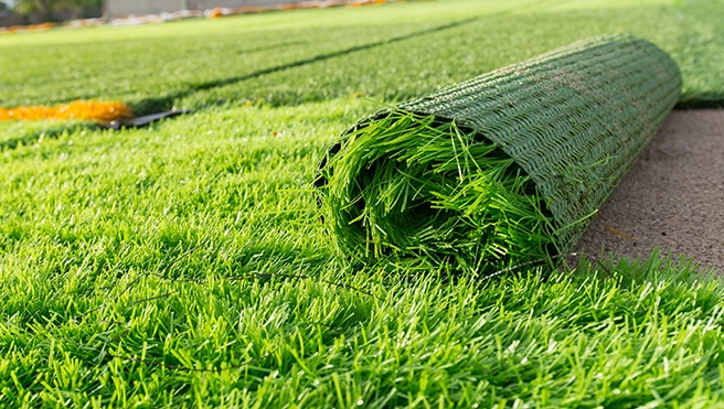 An artificial turf lawn with one roll of synthetic grass partially installed.