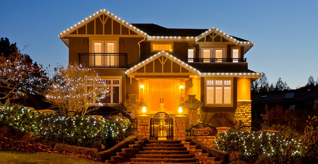 Holiday lighting on 2 story home at dusk.