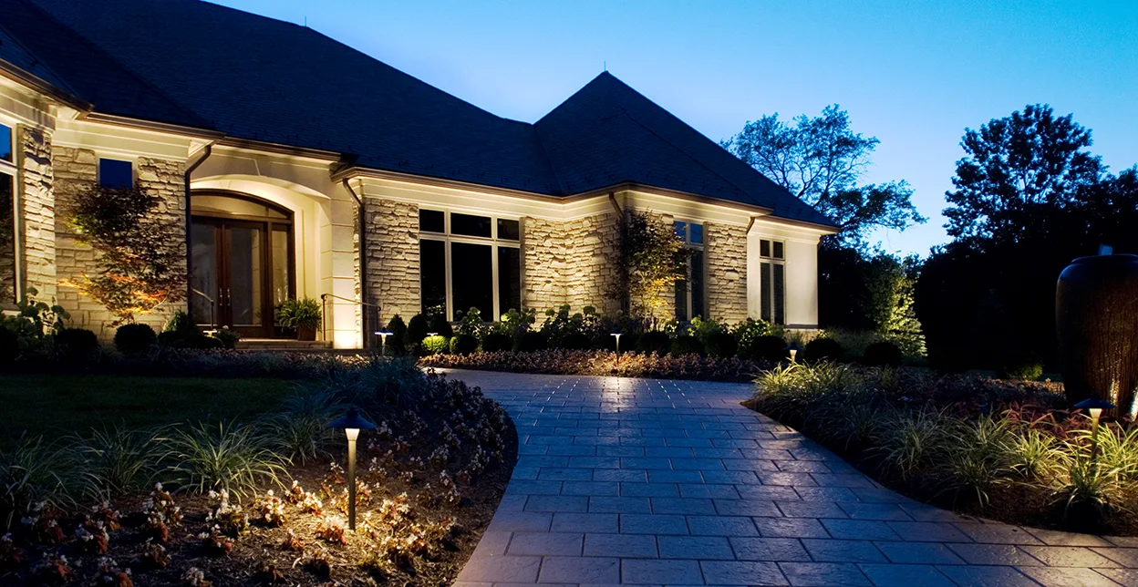 A home at dusk lit with outdoor ground lighting.