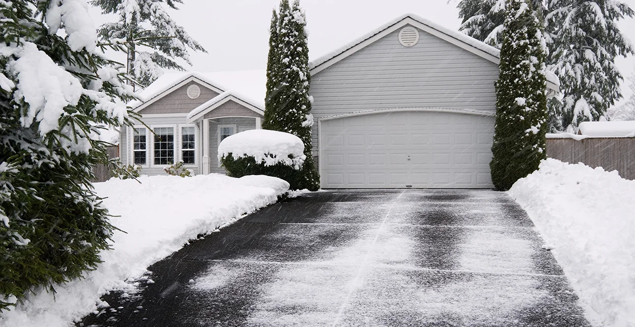 Snow cleared from a home's blacktop driveway.