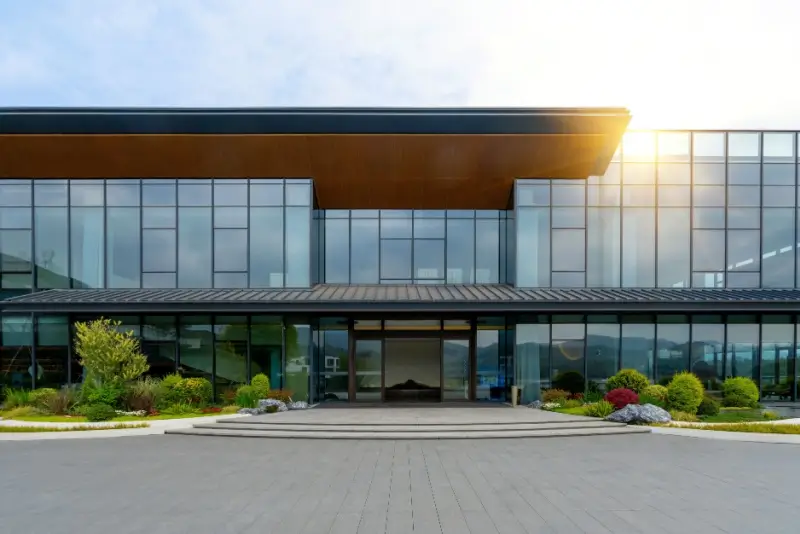 Office building with bushes, trees and grass landscape.