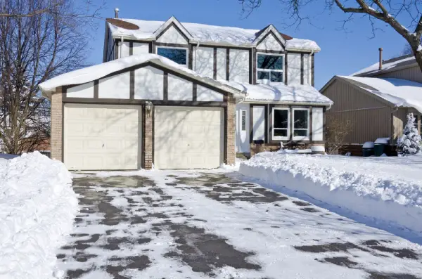 House in the winter with driveway cleared of snow.