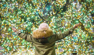 a person standing in front of lit Christmas tree